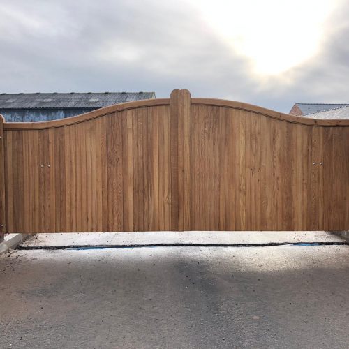 Front view of electric gates made from oak in a swan neck design