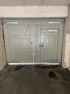Link to our range of driveway gates that can have a wicket gate fitted into. A wicket gate that allows pedestrian access through a larger wooden gate. The image shows the rear view of an entrance gate made from hardwood painted light grey with silver galvanised hinges and gate latches which also can be locked using a key.