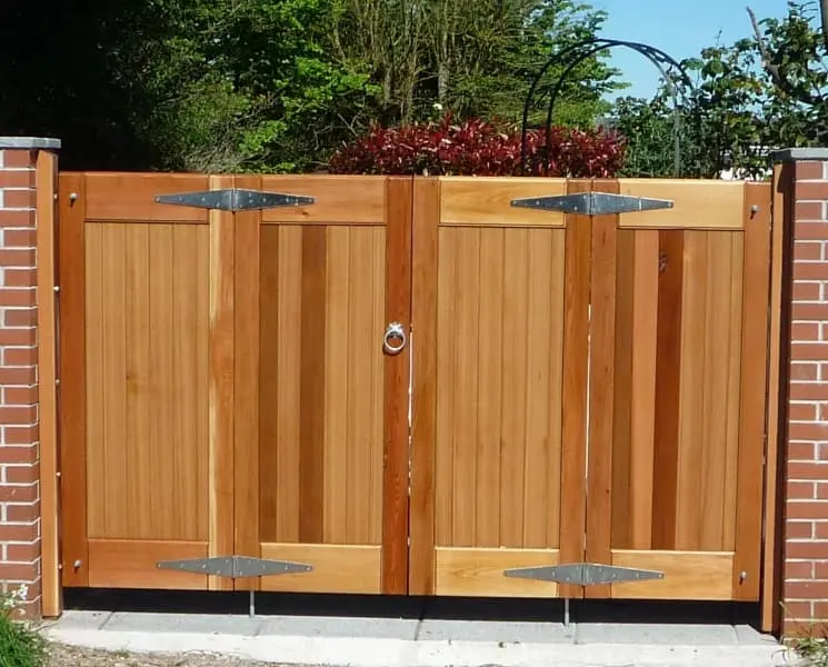 Link to our range of Bi folding Wooden Gates showing a Flat top bifolding wooden gate made from western red cedar fitted to battens between two brick piers with a gate lock.
